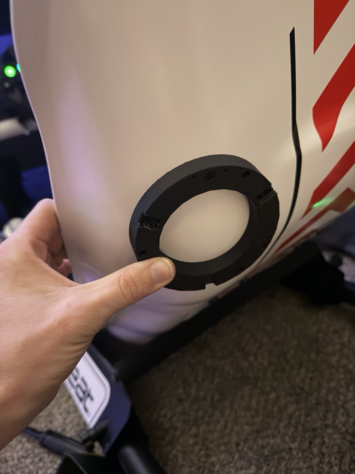 A hand holding the printed mounting ring against the rounded back of the white Playseat shell.